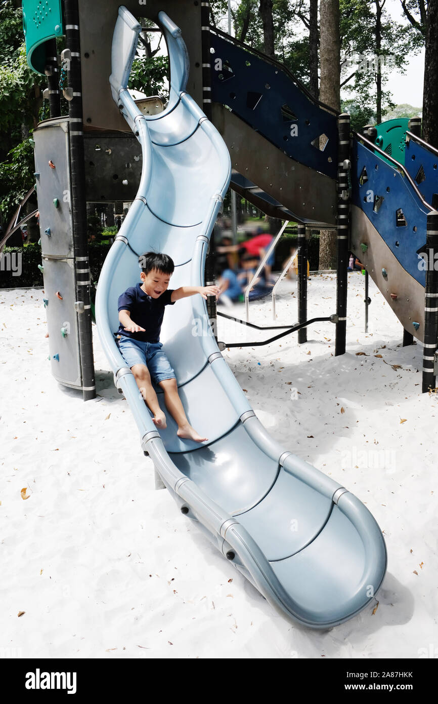 Ho Chi Minh City, Vietnam - October 25, 2017: Active boy sliding down in public playground Stock Photo