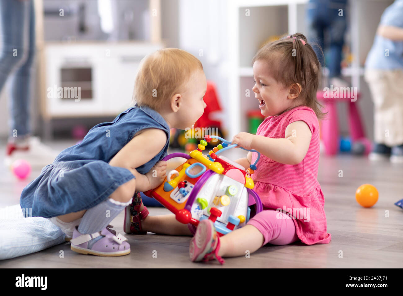 Child girl taking toy away another kid. Babies adaptation in kindergarten Stock Photo