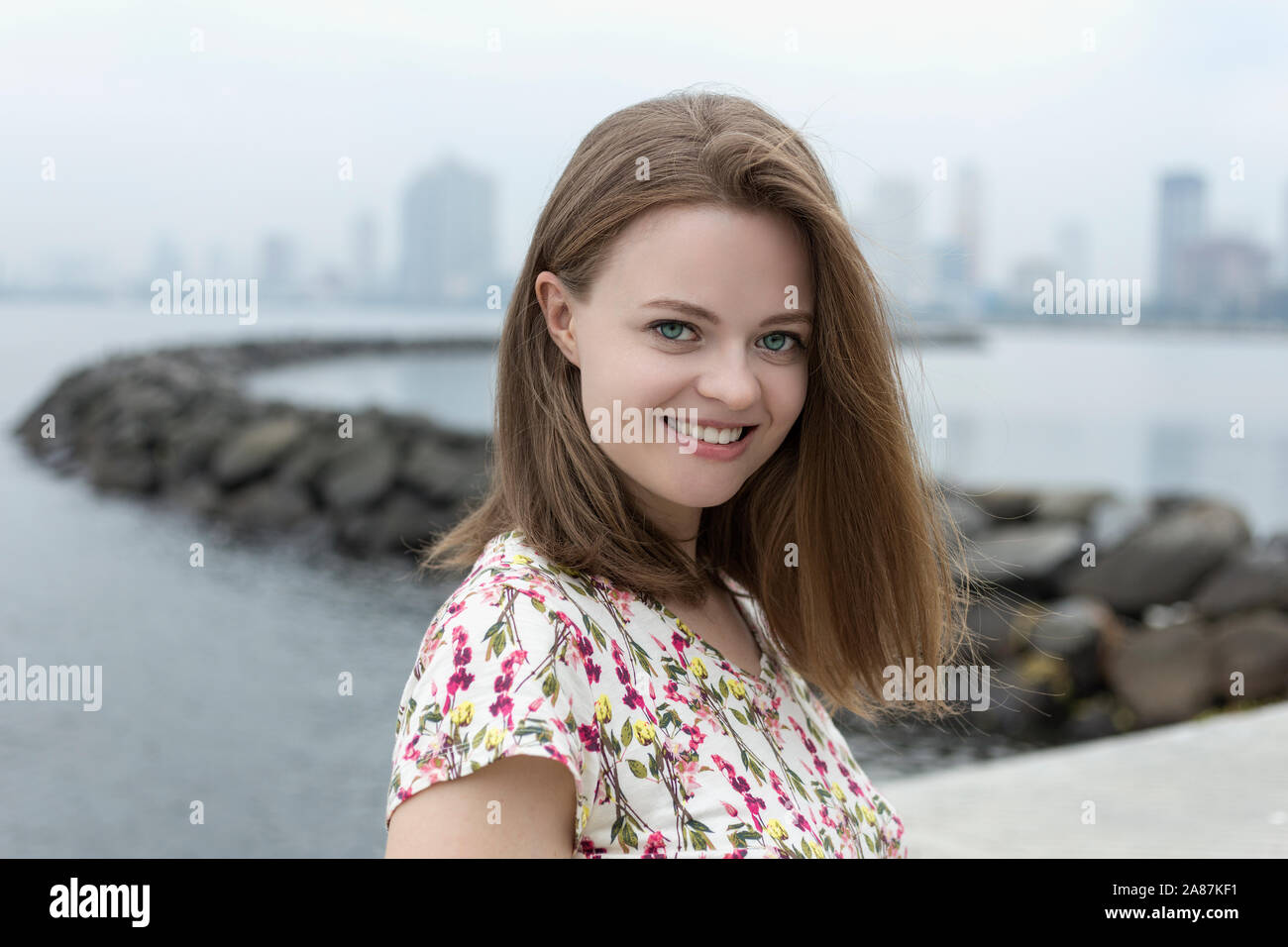 Portrait of smiling pretty beautiful attractive caucasian woman girl in flowery shirt in Harbor Square, Manila bay Stock Photo