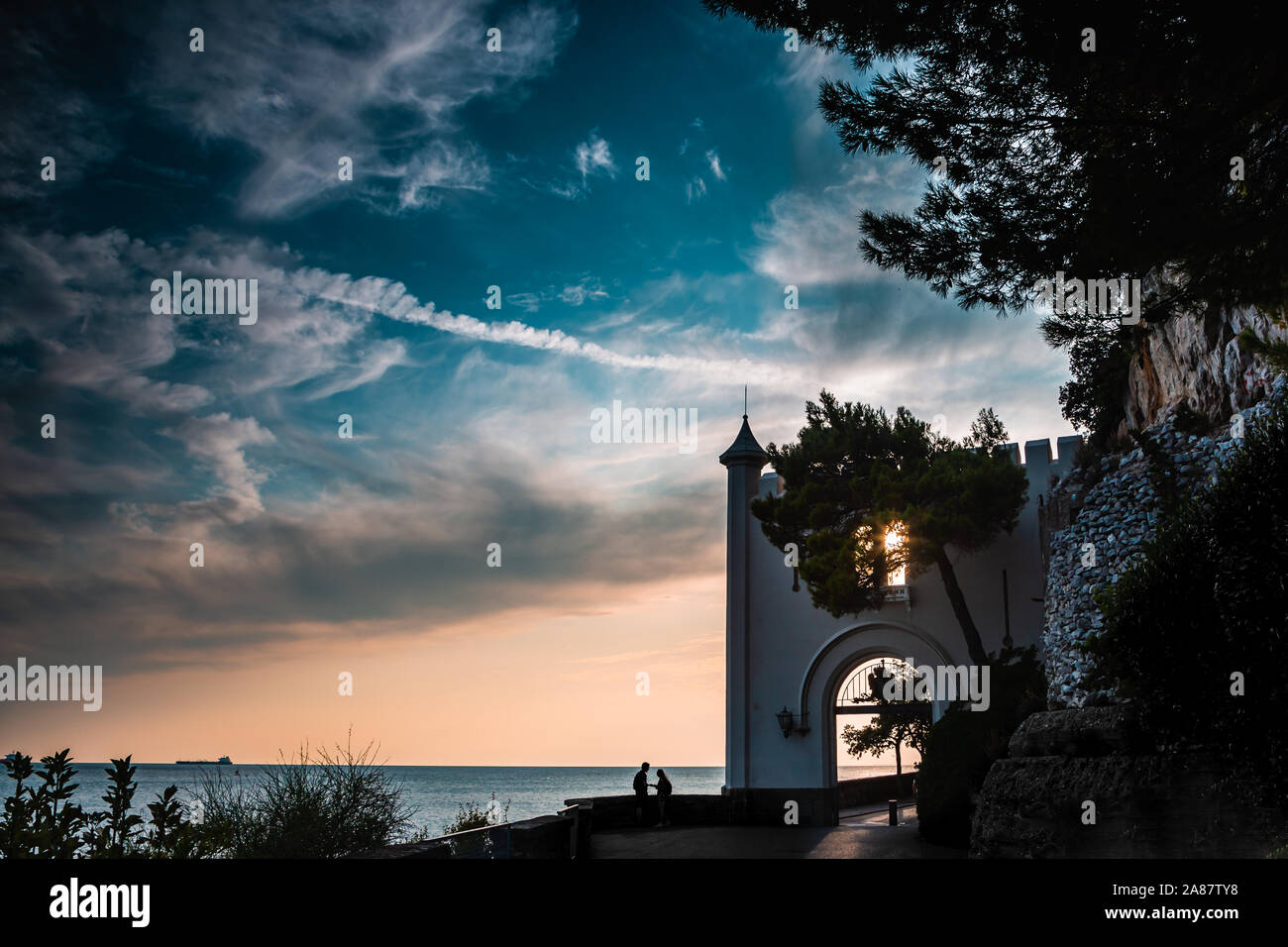 Entrance of the Miramare Castle in Trieste Italy in Europe next to the mediterranean sea with a couple while sunset. Dramatic view of the sky. The cou Stock Photo