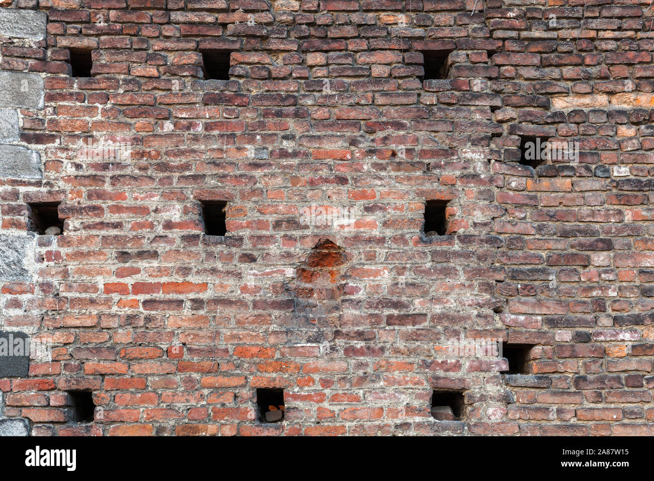 Old grungy brick wall with small holes, frontal view, background photo