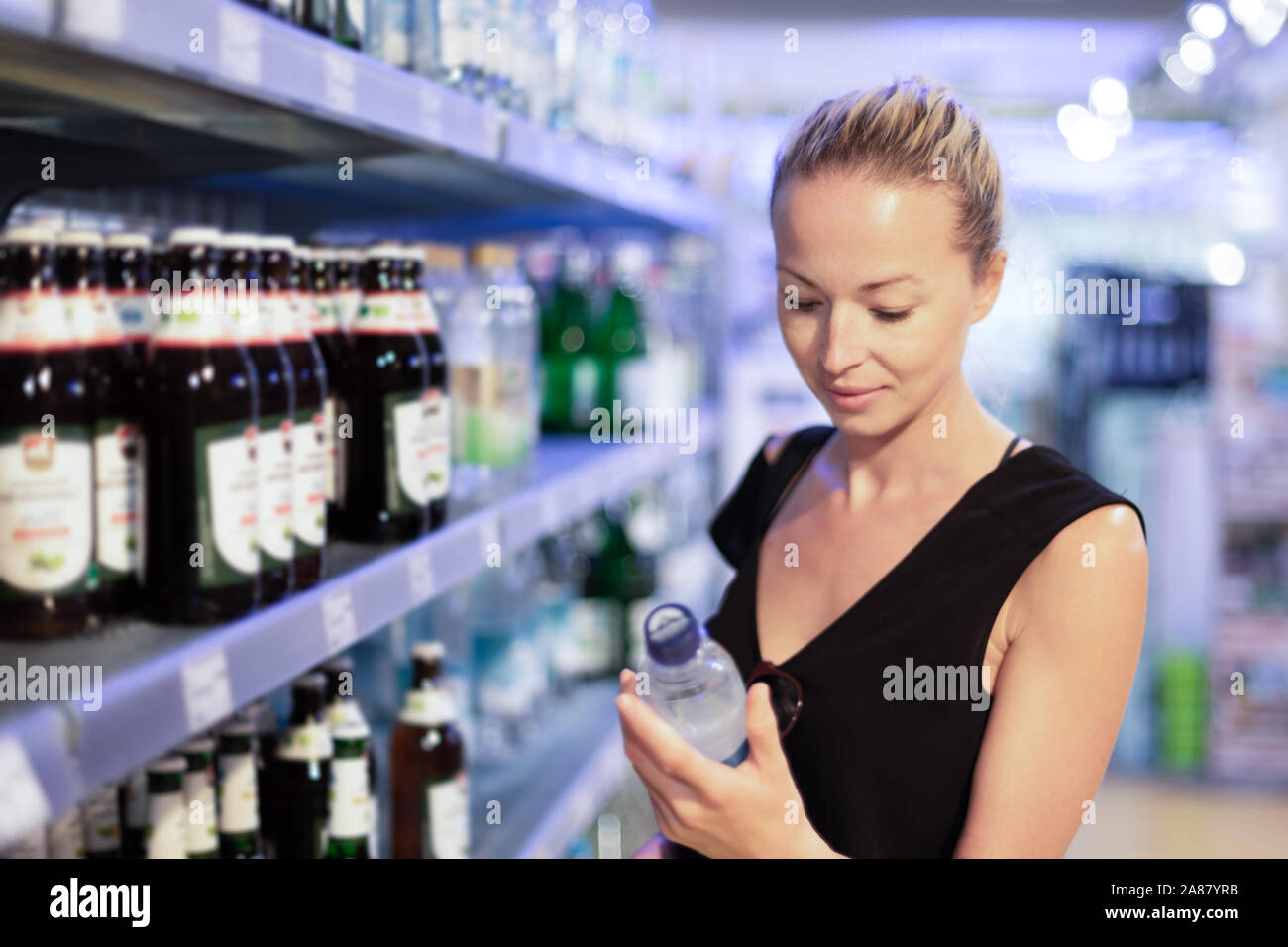 Woman choosing mineral water in grocery store Stock Photo Alamy