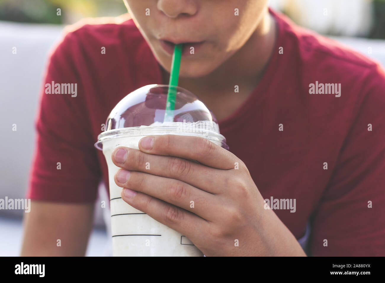 https://c8.alamy.com/comp/2A880YX/close-up-view-of-a-young-boy-hand-holding-a-glass-with-smoothie-mouth-with-drinking-straw-in-background-teen-drinks-a-cold-beverage-outside-in-the-g-2A880YX.jpg