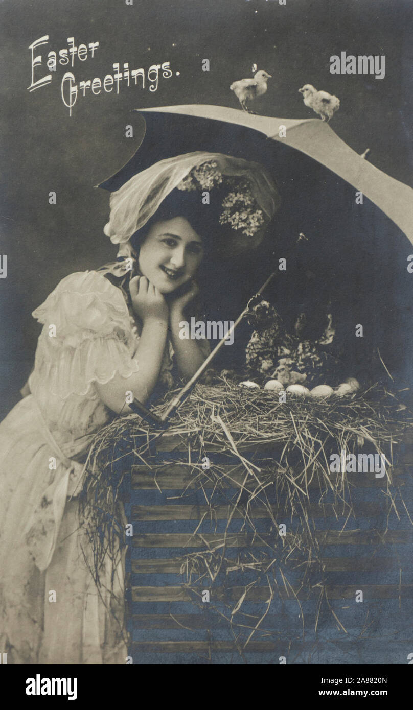 Vintage photograph postcard with Easter Greetings, smiling woman with umbrella looking at eggs in the hay, posted in USA in 1908 Stock Photo