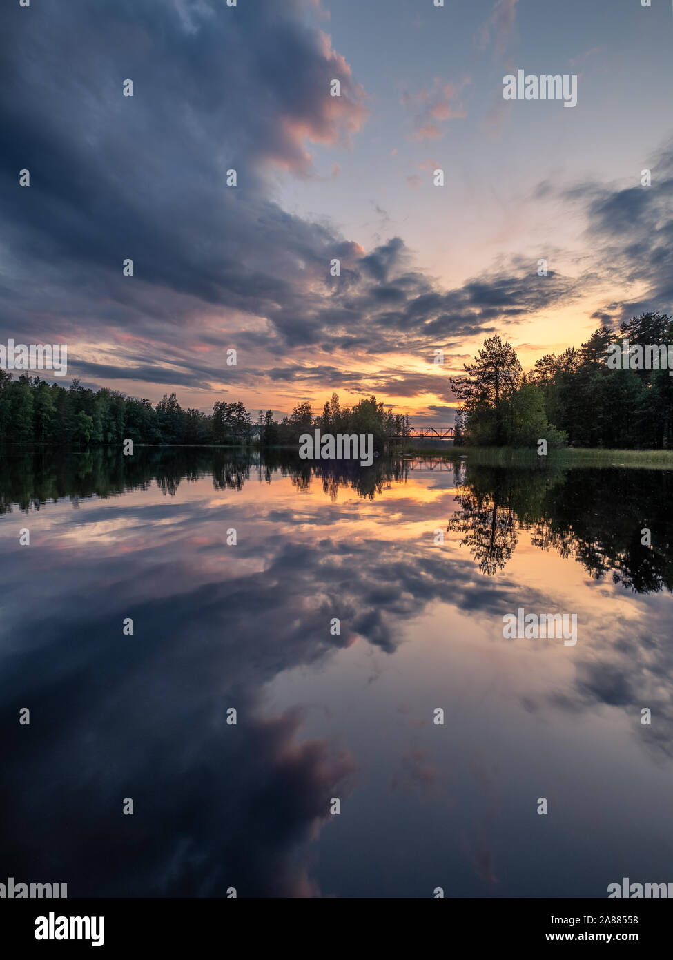 Dramatic clouds and sunset with beautiful lake reflection at summer evening in Finland Stock Photo
