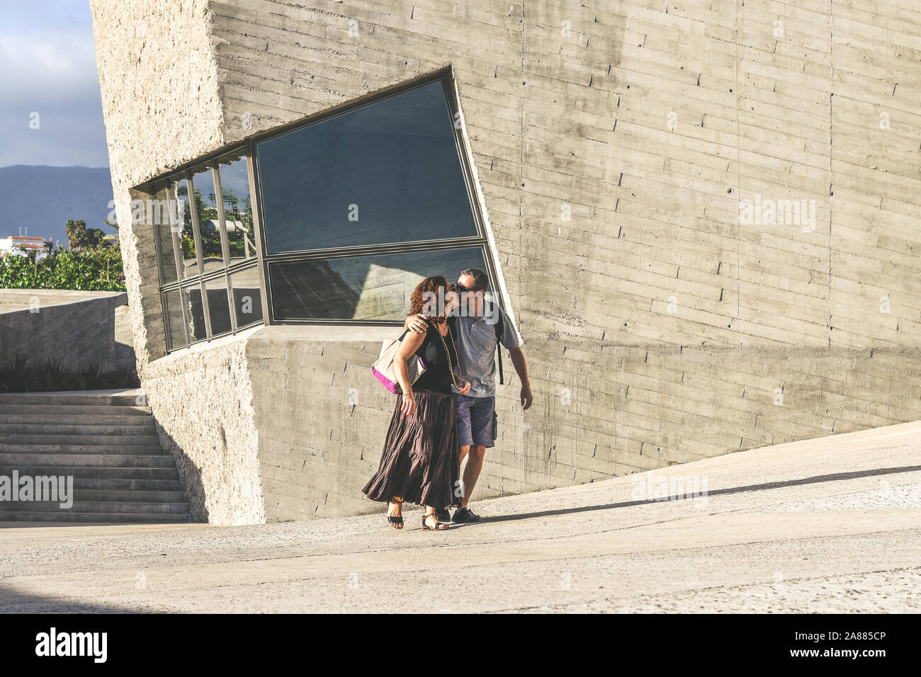 Couple of tourists is kissing in the city discovering new places. Man and woman walks in a modern urban context. People having fun in a touristic city Stock Photo