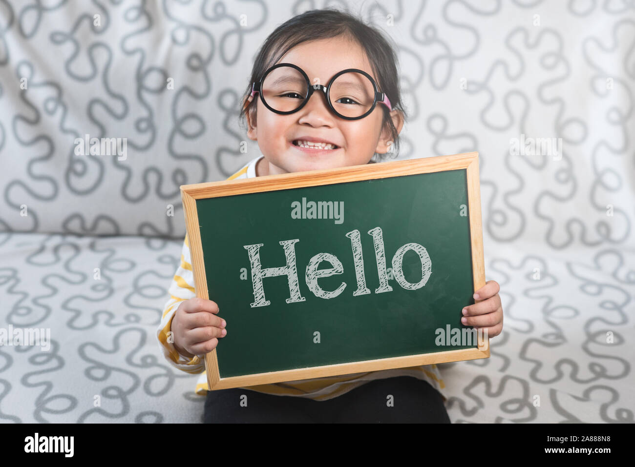 Little asian girl holding a chalkboard with a word HELLO. Concept of Hello day, Greetings, Introduction and lifestyle Stock Photo
