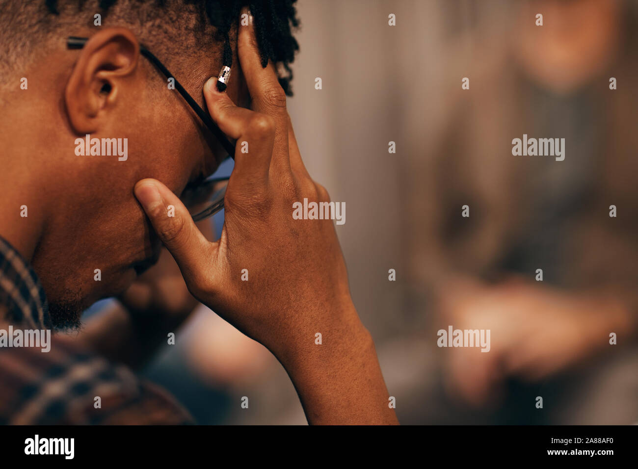 Close-up of African young man holding his head and looking very upset he has problems Stock Photo