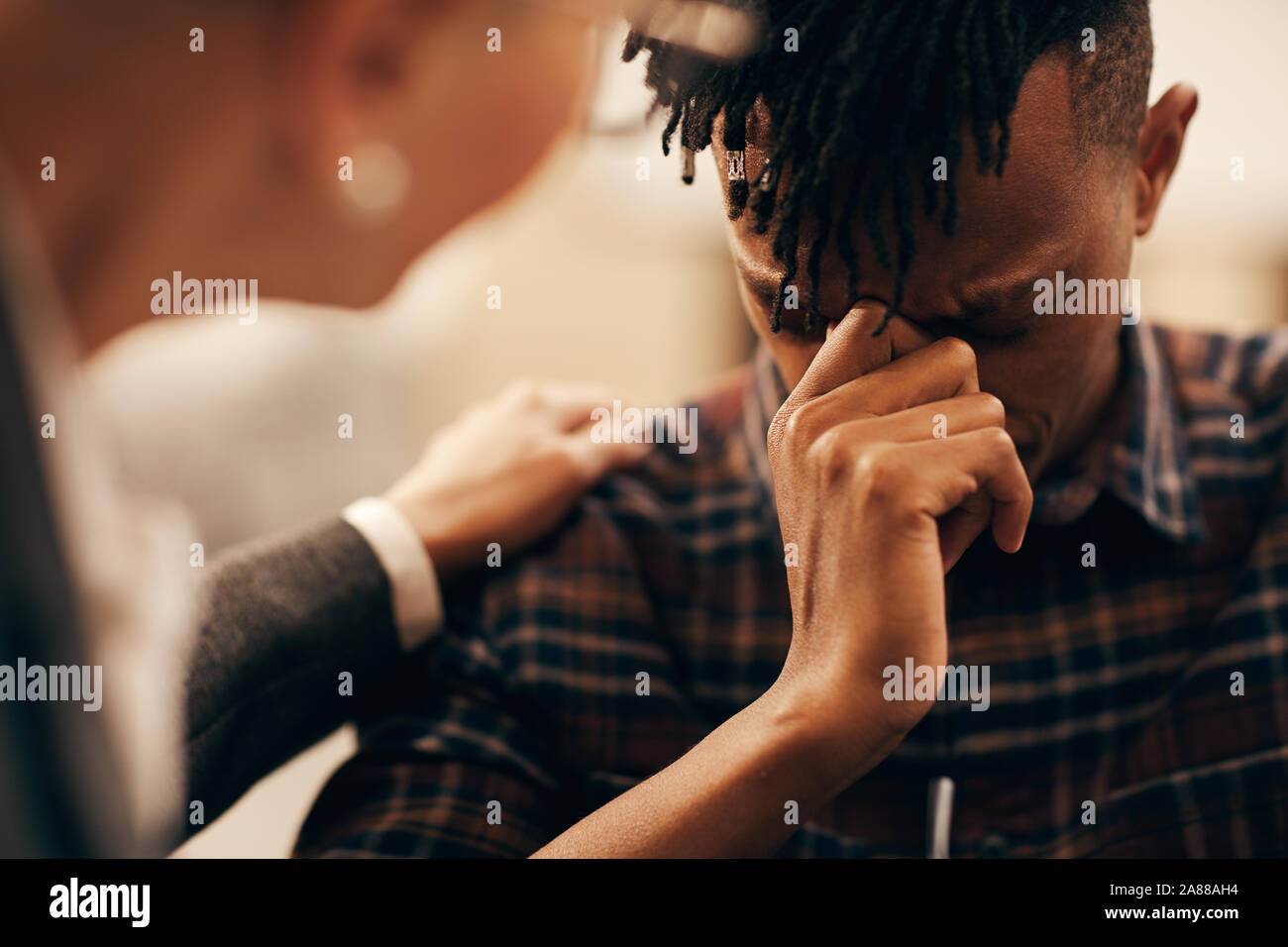 Young African man worried about his problem and telling about it to the woman who comforting him Stock Photo