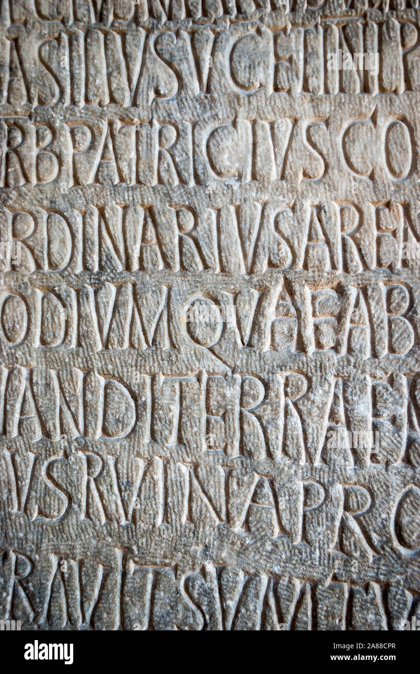 Latin text written in stone. Full frame Roman text carved into a flat stone wall. Stock Photo