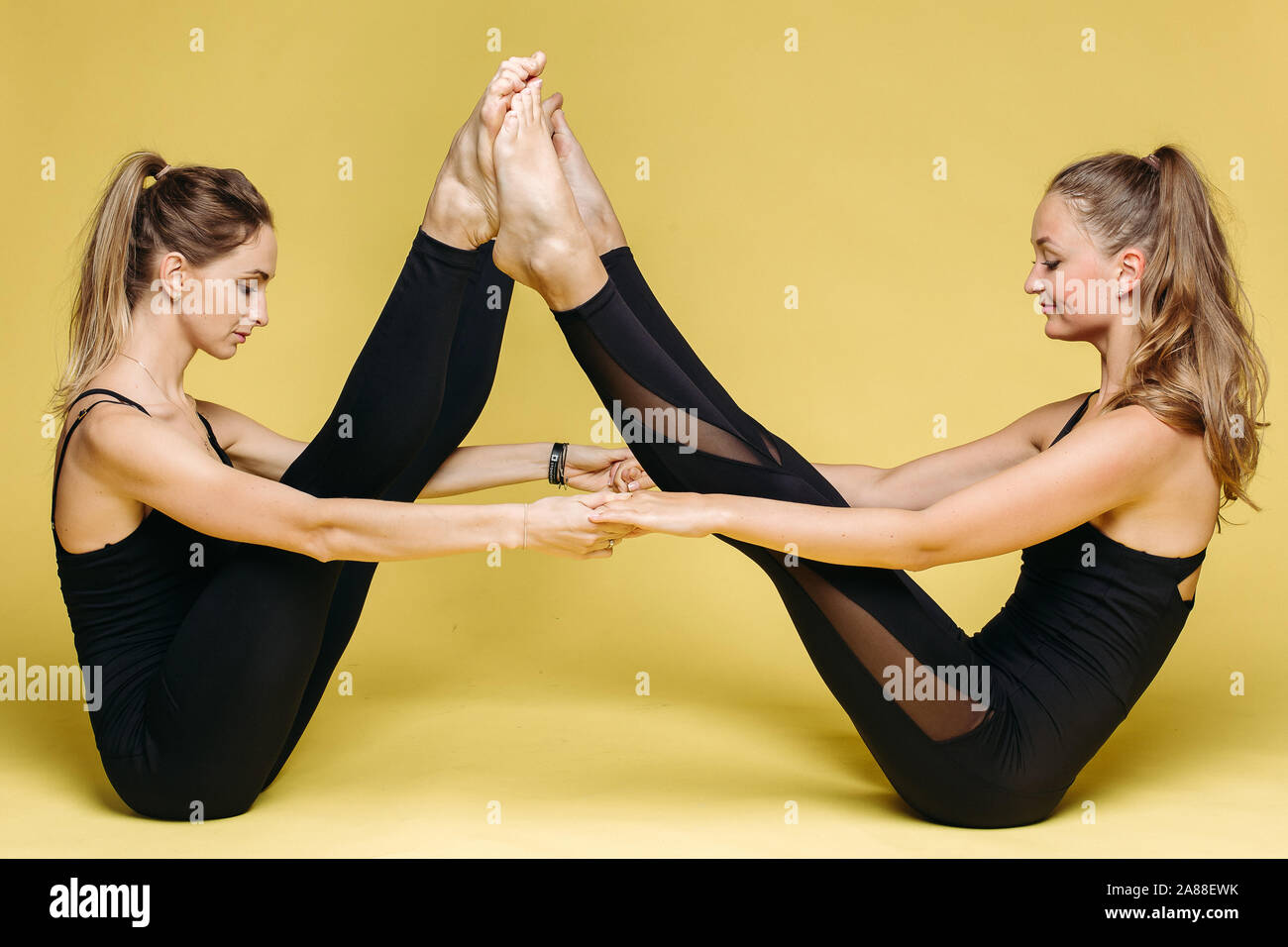 Two athletics girls in black sport wear doing yoga exercise Stock