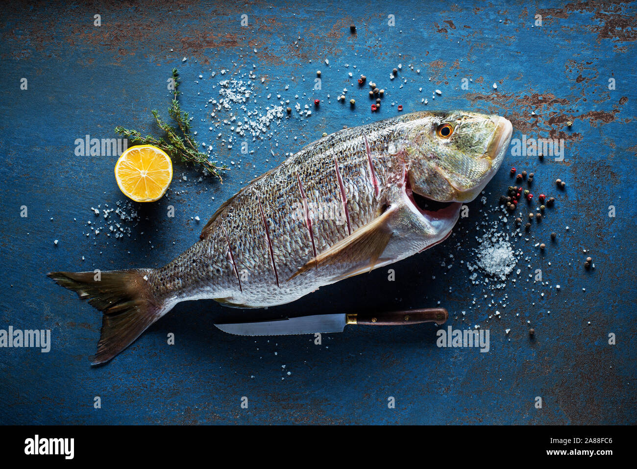 Delicious fresh fish with spices on vintage background. Healthy diet eating or cooking concept Stock Photo