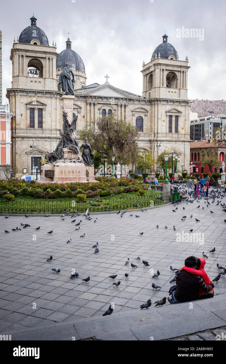 Couple sitting on Plaza Murillo in the Historic District with the Cathedral of Our Lady of Peace in the background, La Paz, Bolivia Stock Photo
