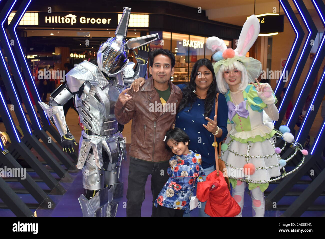 An Asian family is posing with robot costume man and rabbit costume girl with lights in the background in Genting highlands, Malaysia, Asia. Stock Photo