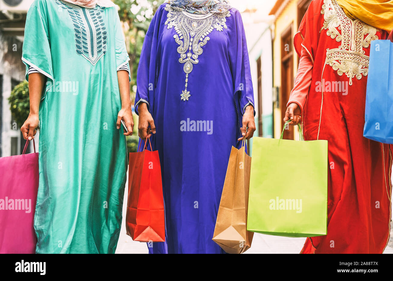 Happy Muslim women doing shopping in the city center - Arabian teen girls having fun buying new traditional Arab clothes in mall Stock Photo