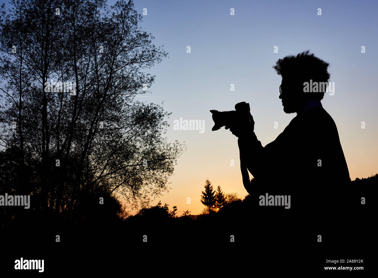 Photographer as silhouette while taking photos at blue hour in nature Stock Photo