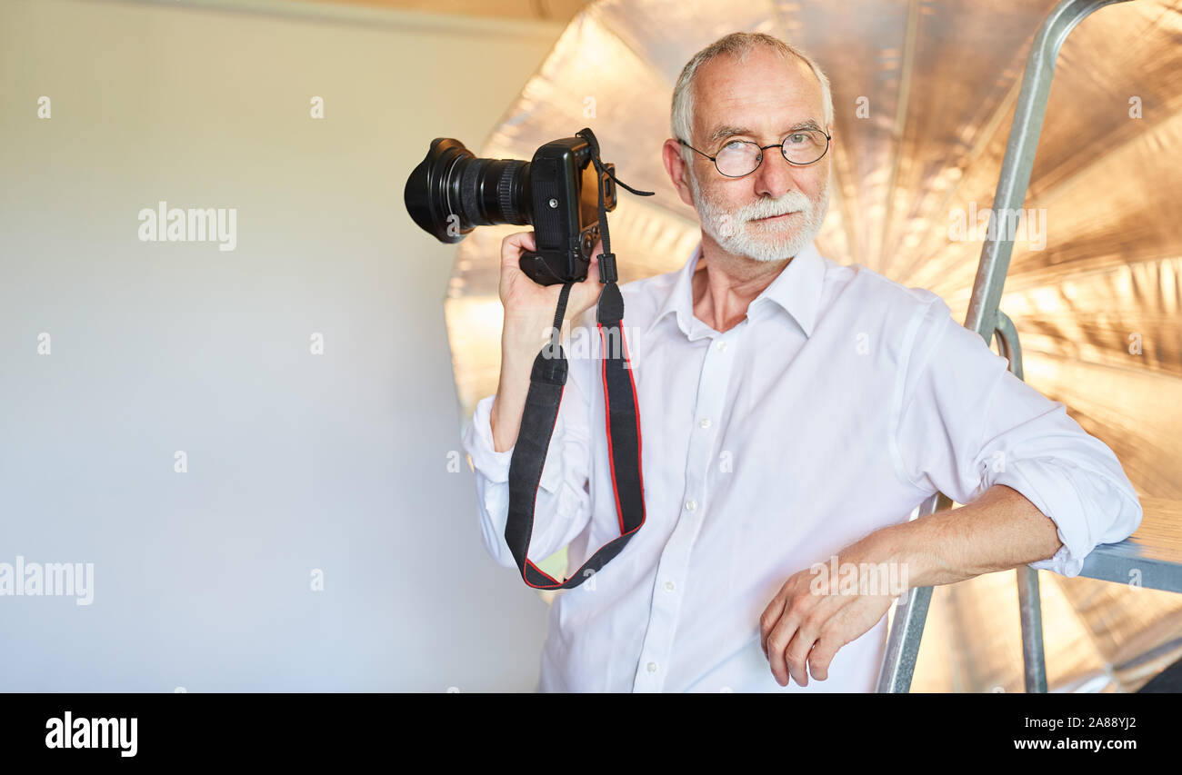 Senior as a cool professional photographer with a camera in the photo studio Stock Photo