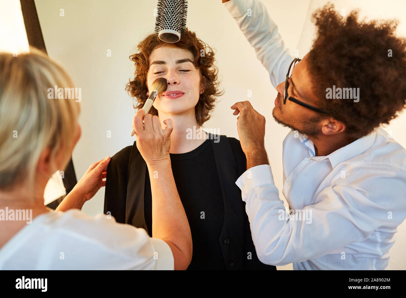 Hairstylist and make-up artist make-up model before a photo shoot Stock Photo