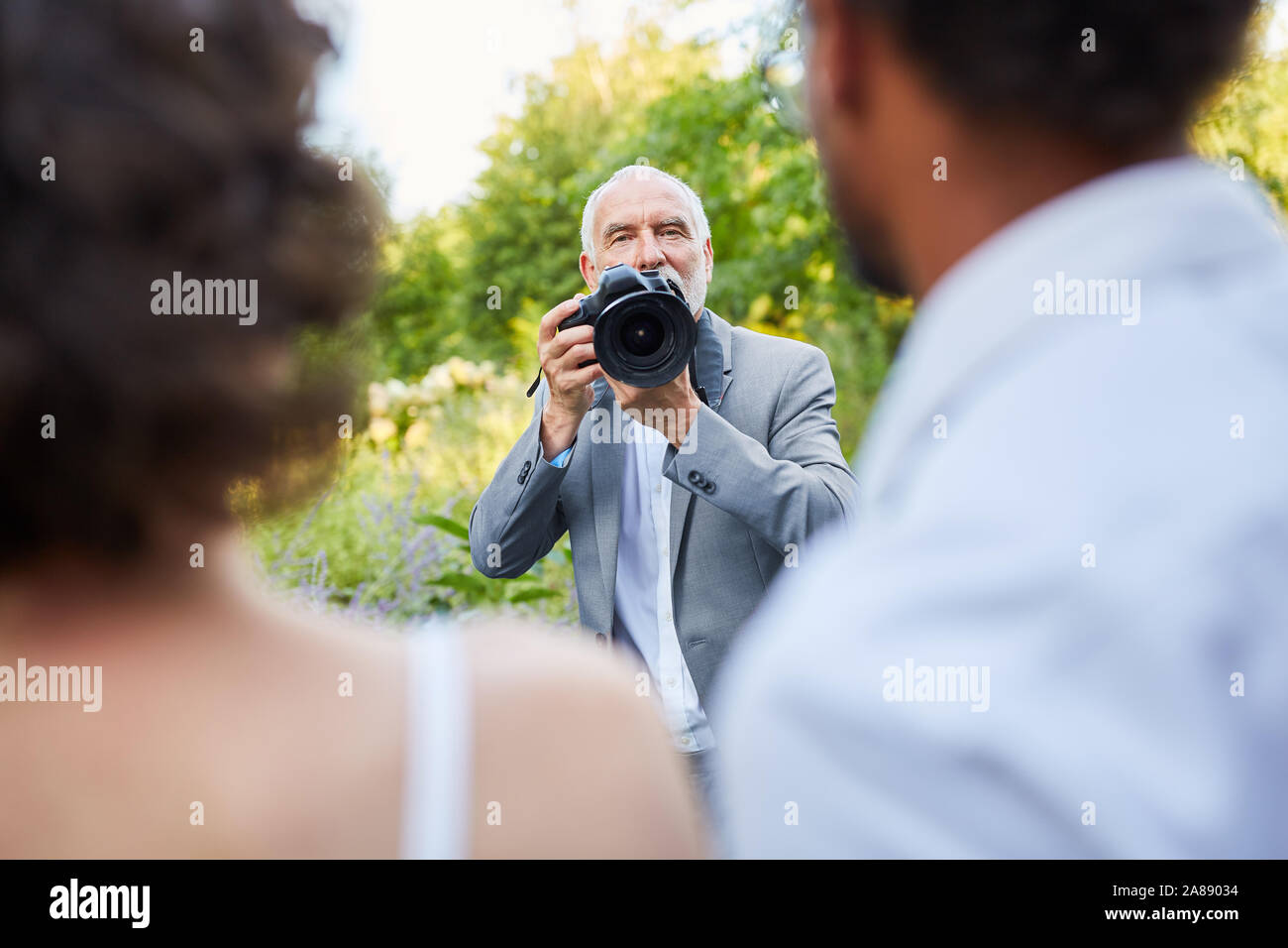 Wedding photographer and newlyweds at the photo shoot in nature Stock Photo