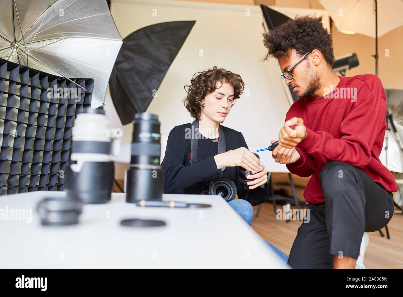 Photo assistant helps photographer with lens cleaning with bellows ...