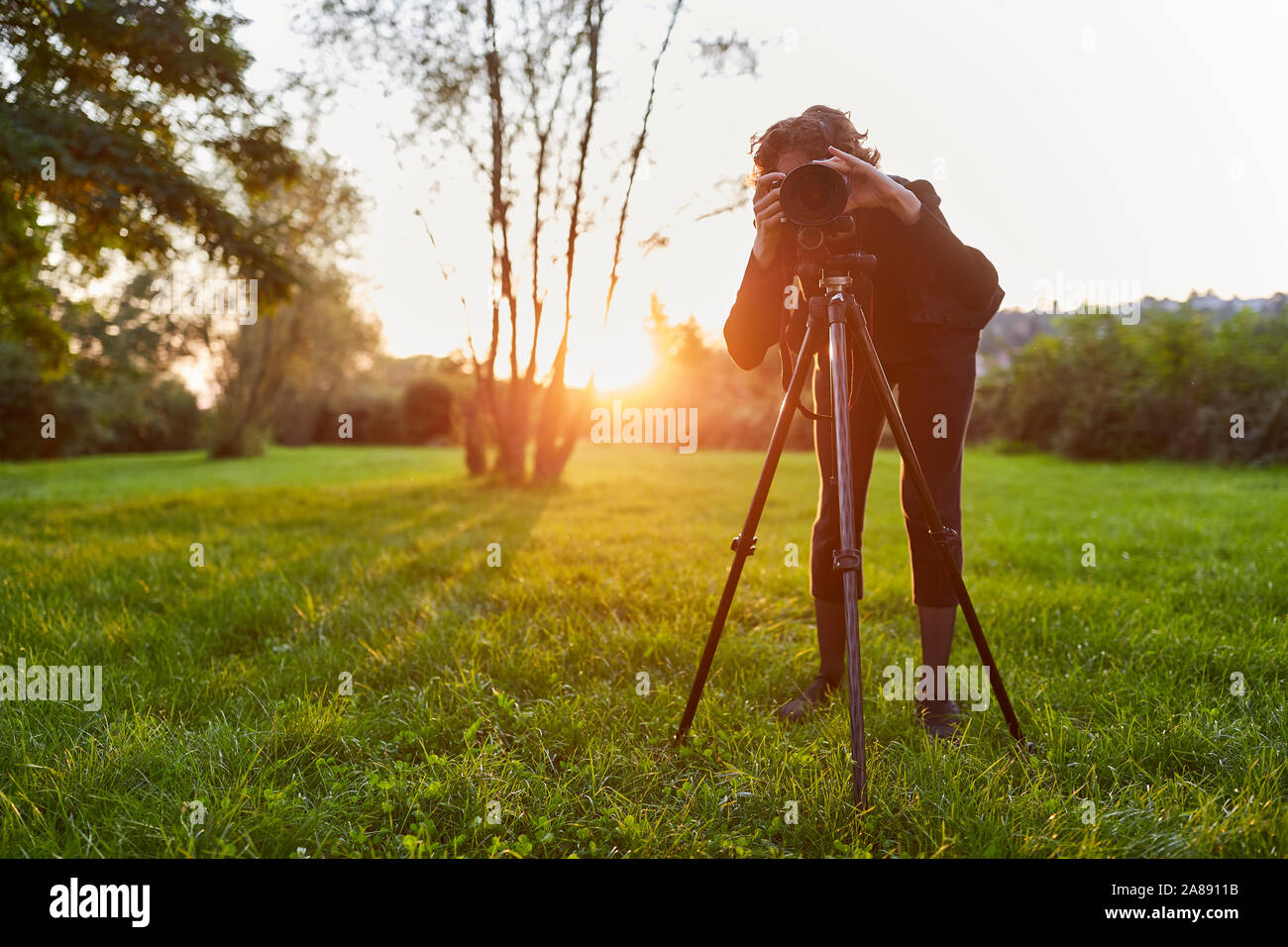 Young woman as landscape photographer with camera on the tripod in the ...