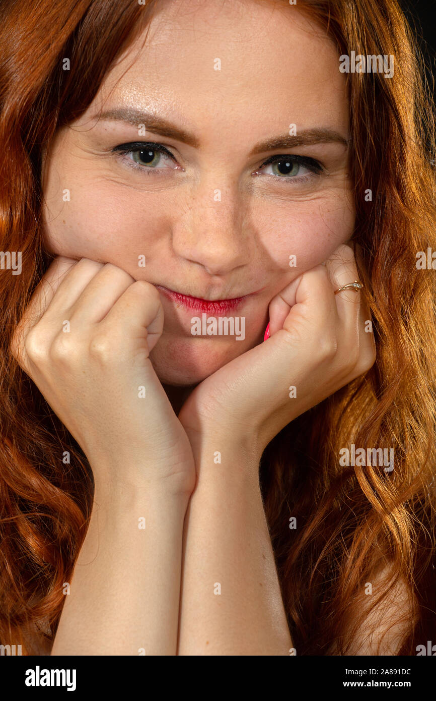 fun shy girl with red hair and inflated cheeks looking at camera closeup portrait Stock Photo