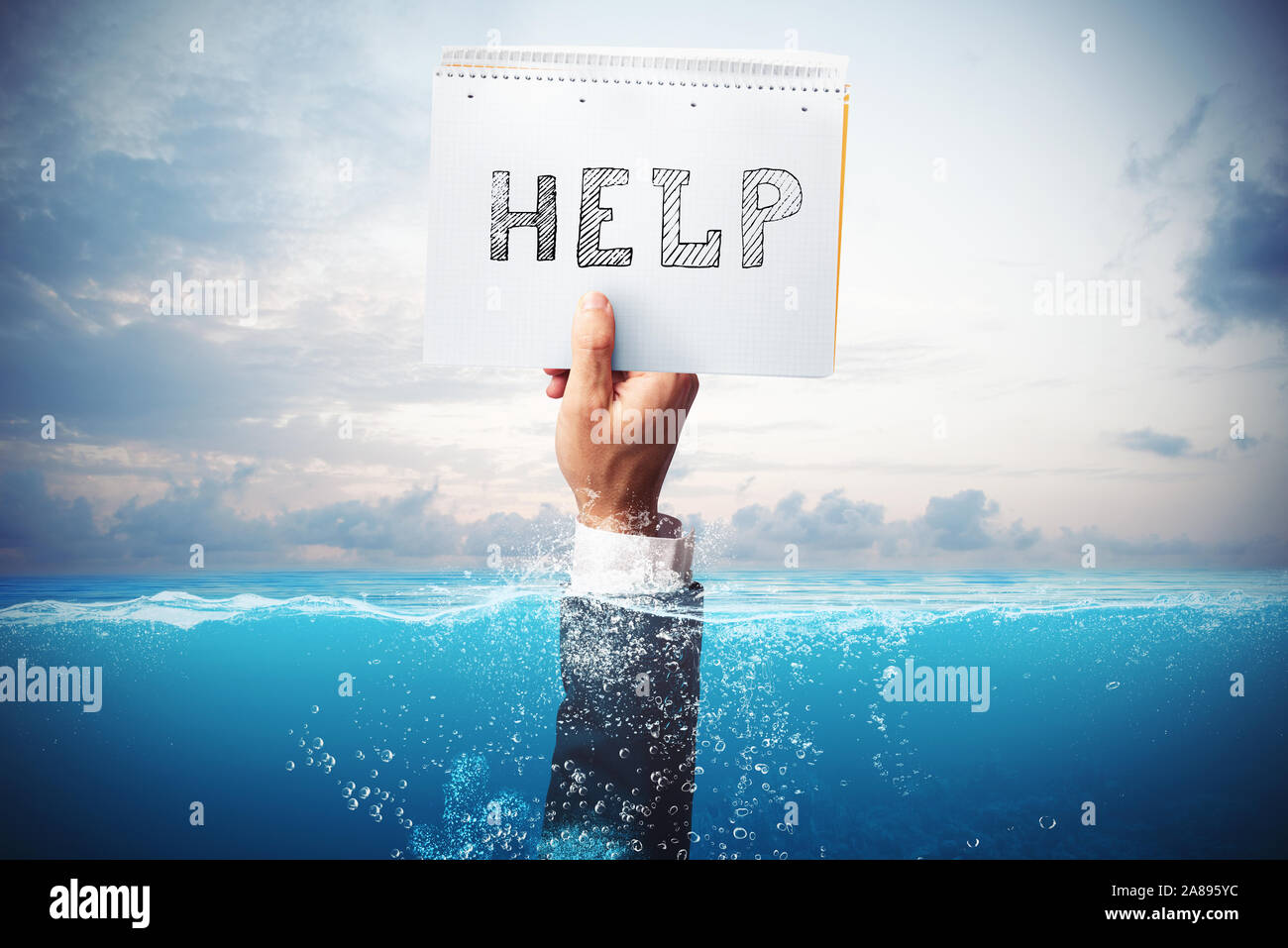 Businessman drowning in the sea with a hand holding a sheet of paper with help written Stock Photo