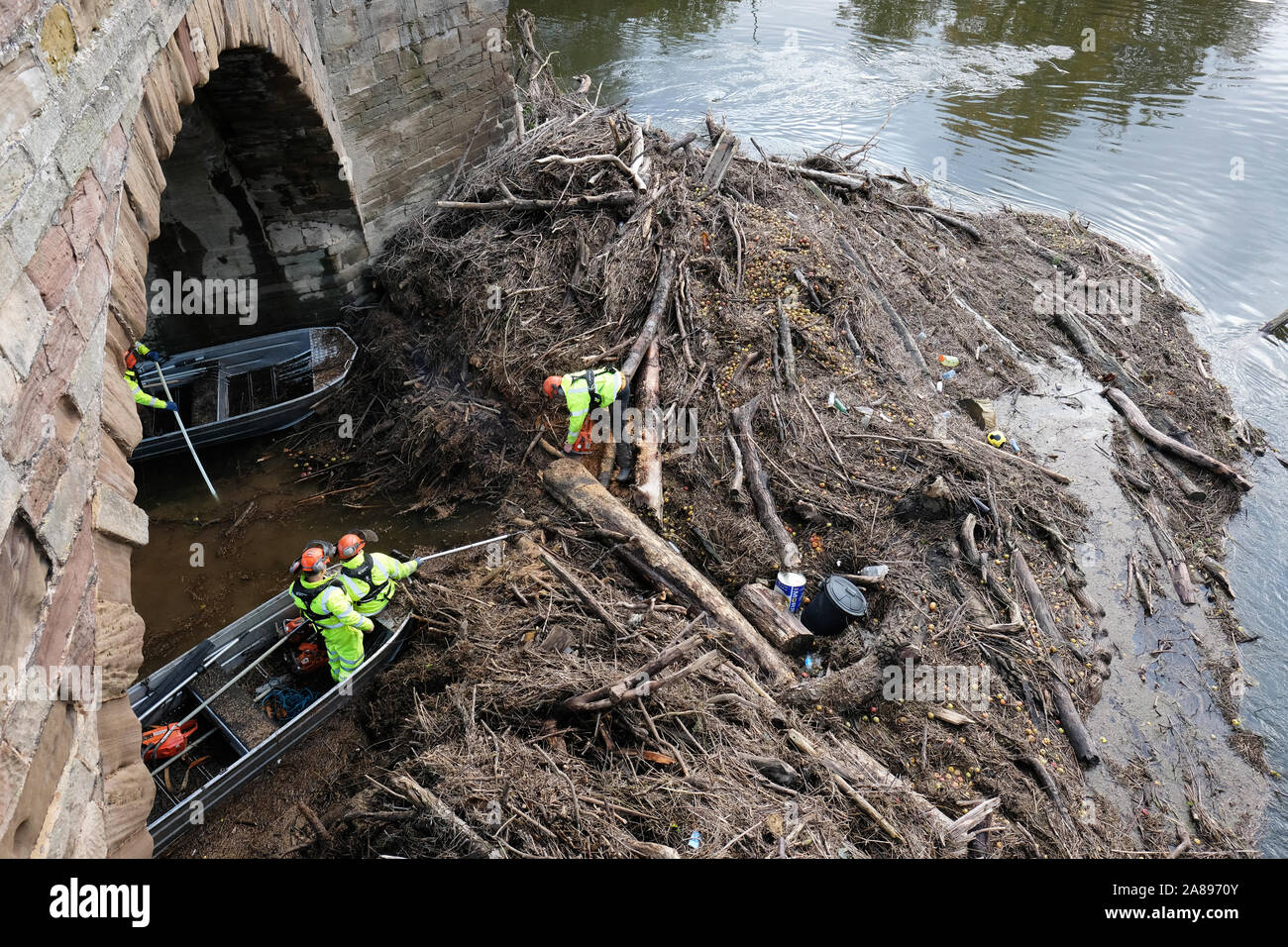 Hereford, Herefordshire, UK - Thursday 7th November 2019 - Environment Agency staff with chain saws and hooks start to clear the huge volume of trees, branches and assorted river debris that is blocking the centre arches of the old medieval Wye Bridge in Hereford. Recent heavy rain last wek saw the River Wye peak at 5.5m in the city, the highest since 1998.  Photo Steven May / Alamy Live News Stock Photo