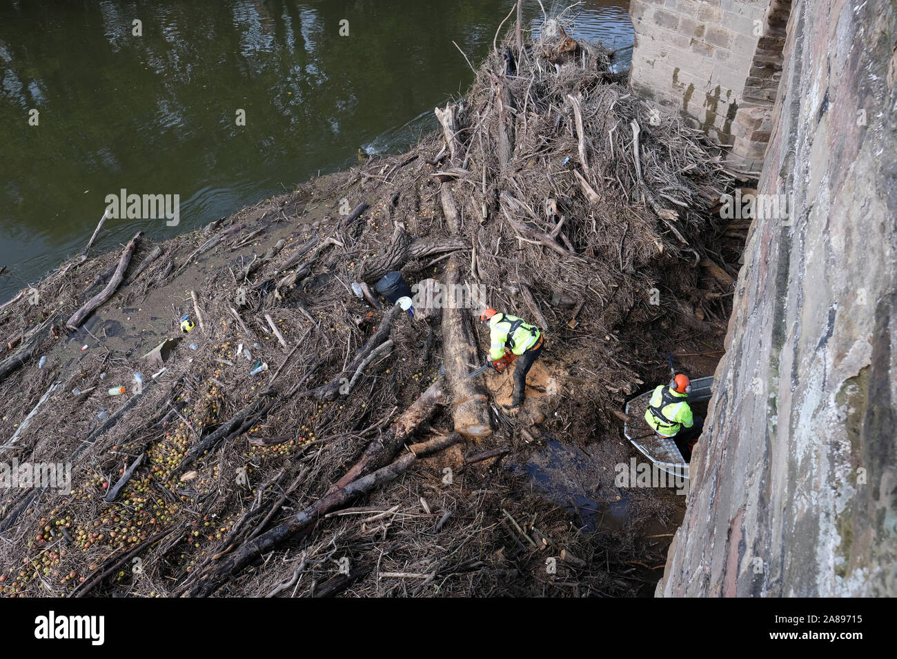 Hereford, Herefordshire, UK - Thursday 7th November 2019 - Environment Agency staff with chain saws and hooks start to clear the huge volume of trees, branches and assorted river debris that is blocking the centre arches of the old medieval Wye Bridge in Hereford. Recent heavy rain last wek saw the River Wye peak at 5.5m in the city, the highest since 1998.  Photo Steven May / Alamy Live News Stock Photo
