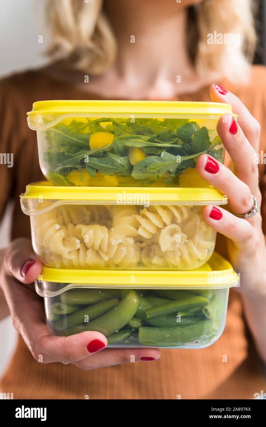 Woman holding stack of food in plastic containers Stock Photo