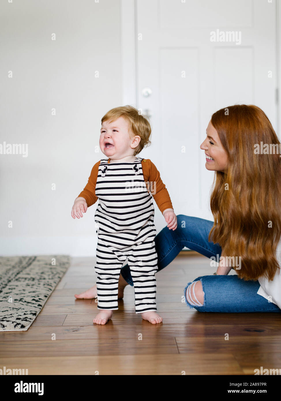 Mother smiling by her crying son Stock Photo