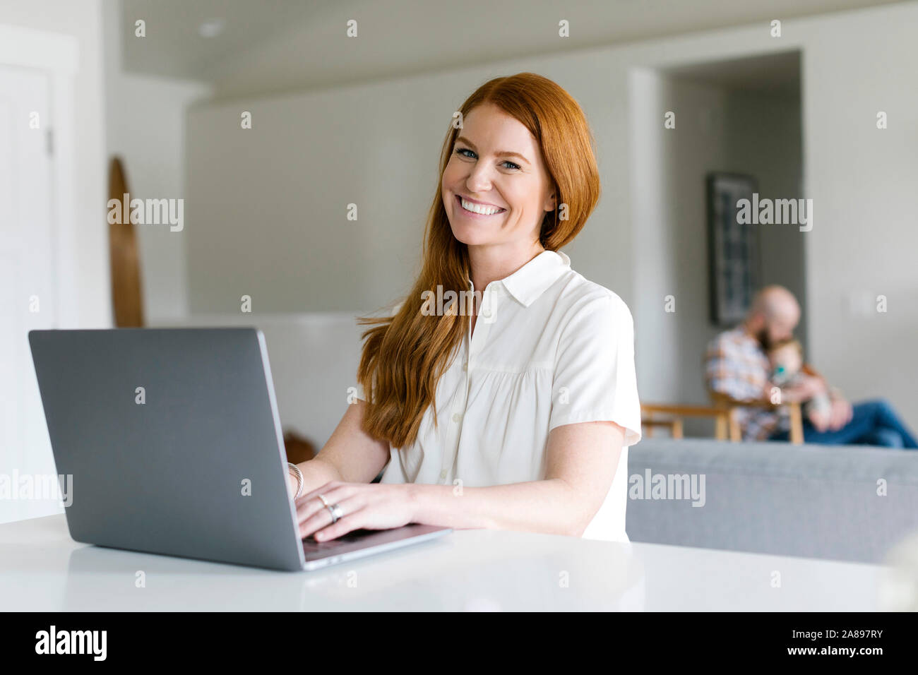 Smiling woman using laptop at home Stock Photo