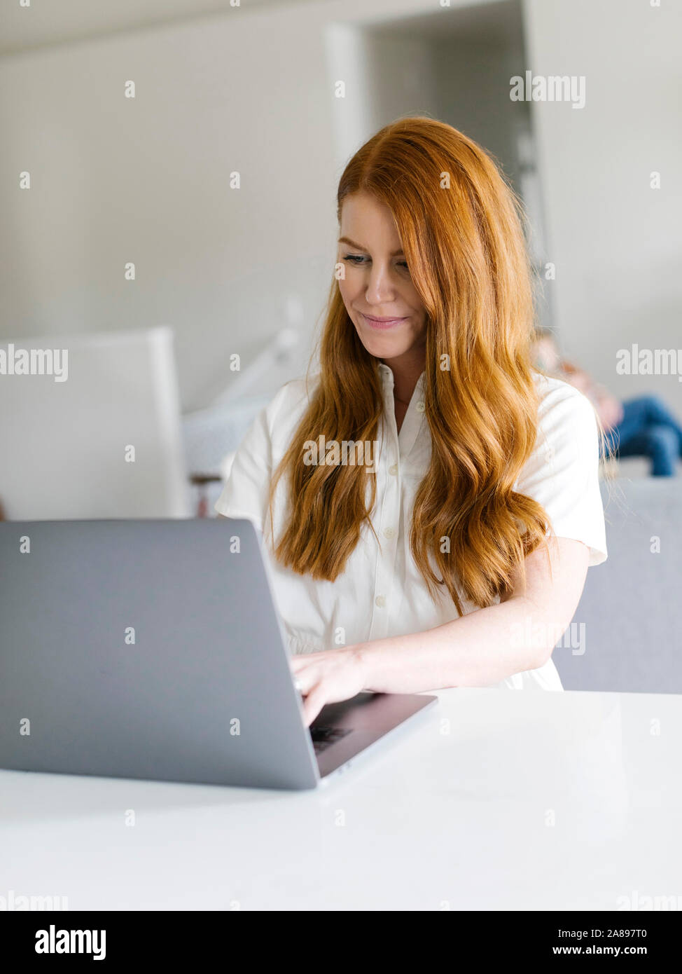 Redheaded woman using laptop at home Stock Photo