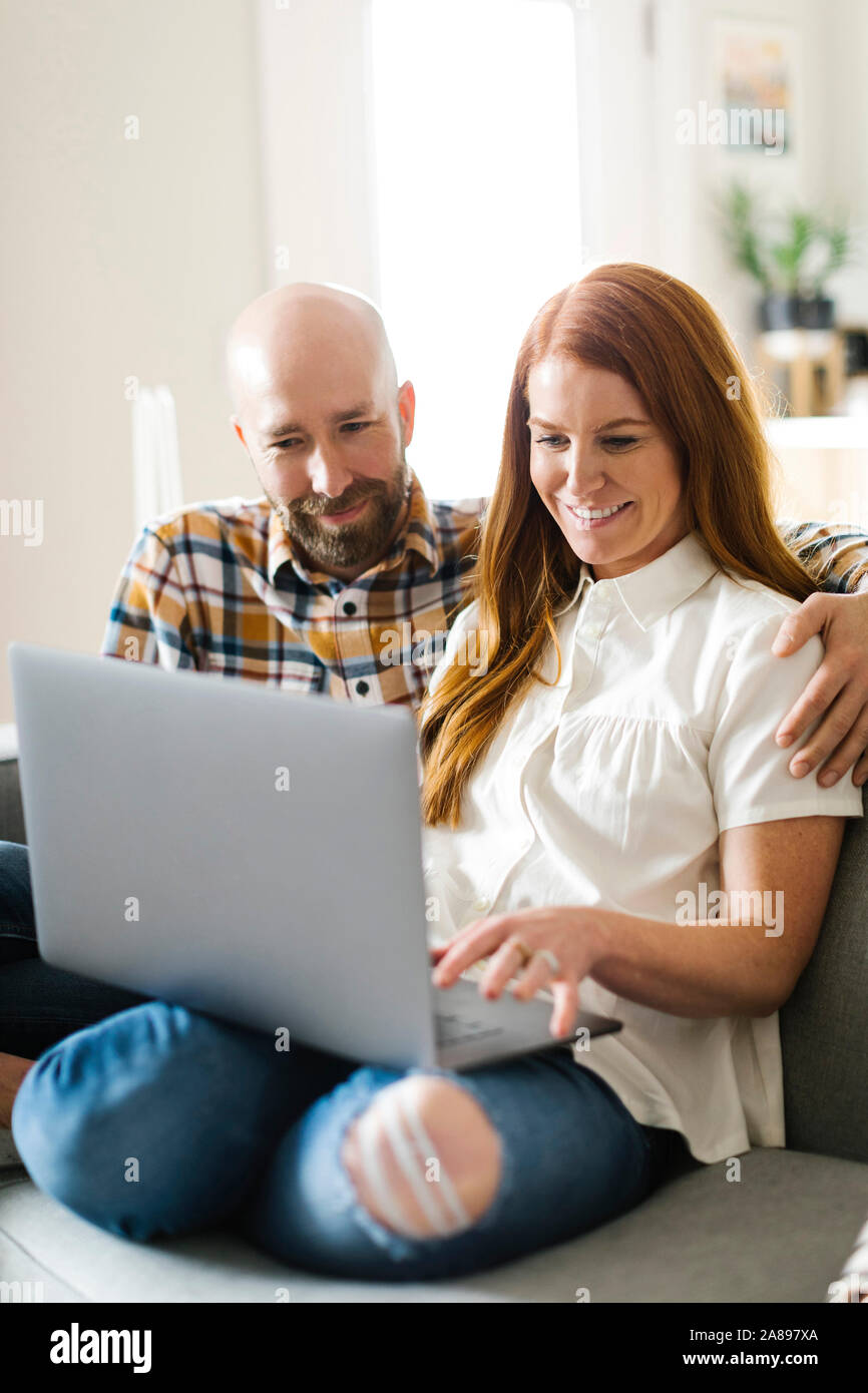 Couple using laptop on sofa Stock Photo - Alamy