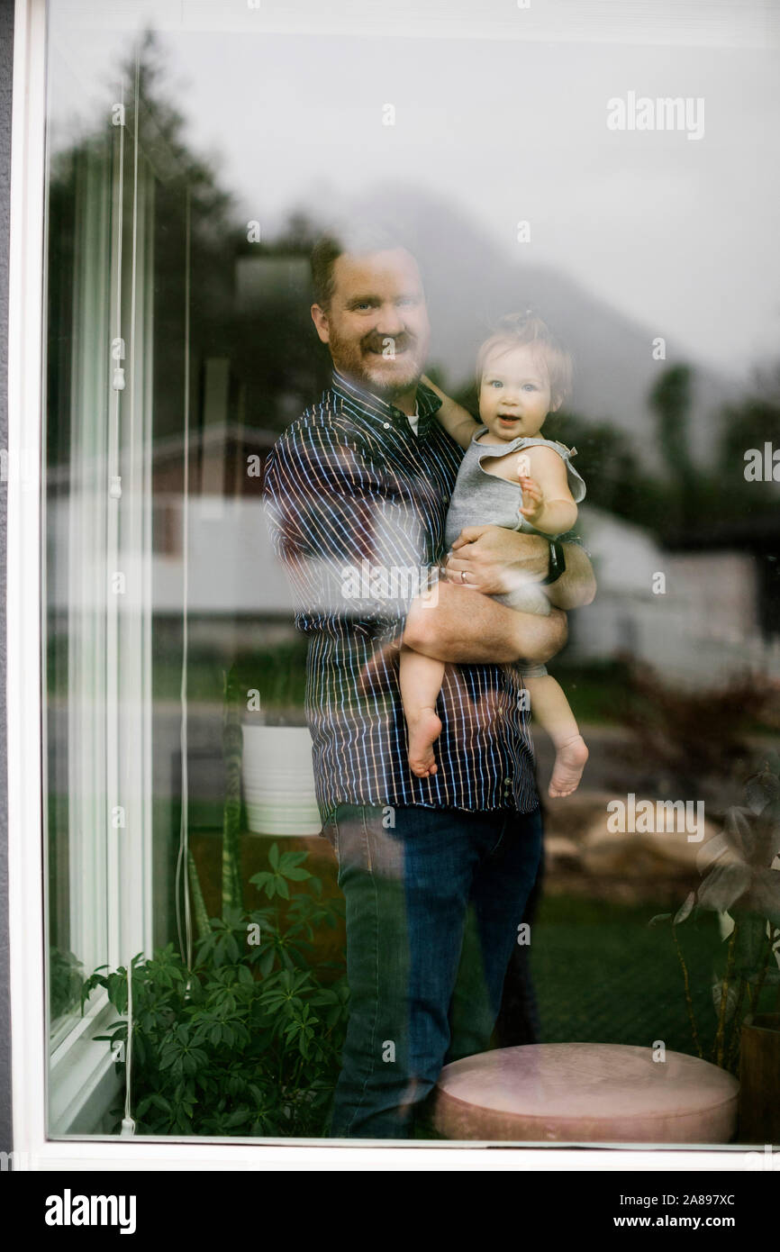 Father holding his daughter behind window Stock Photo