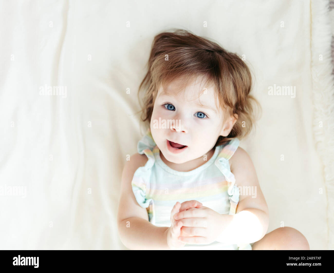 Baby girl lying on bed hi-res stock photography and images - Alamy