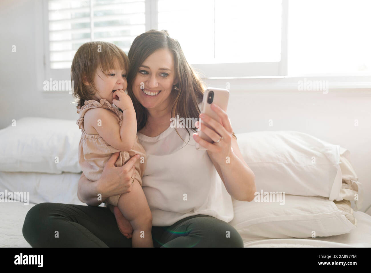 Mother and daughter taking selfie on bed Stock Photo Alamy