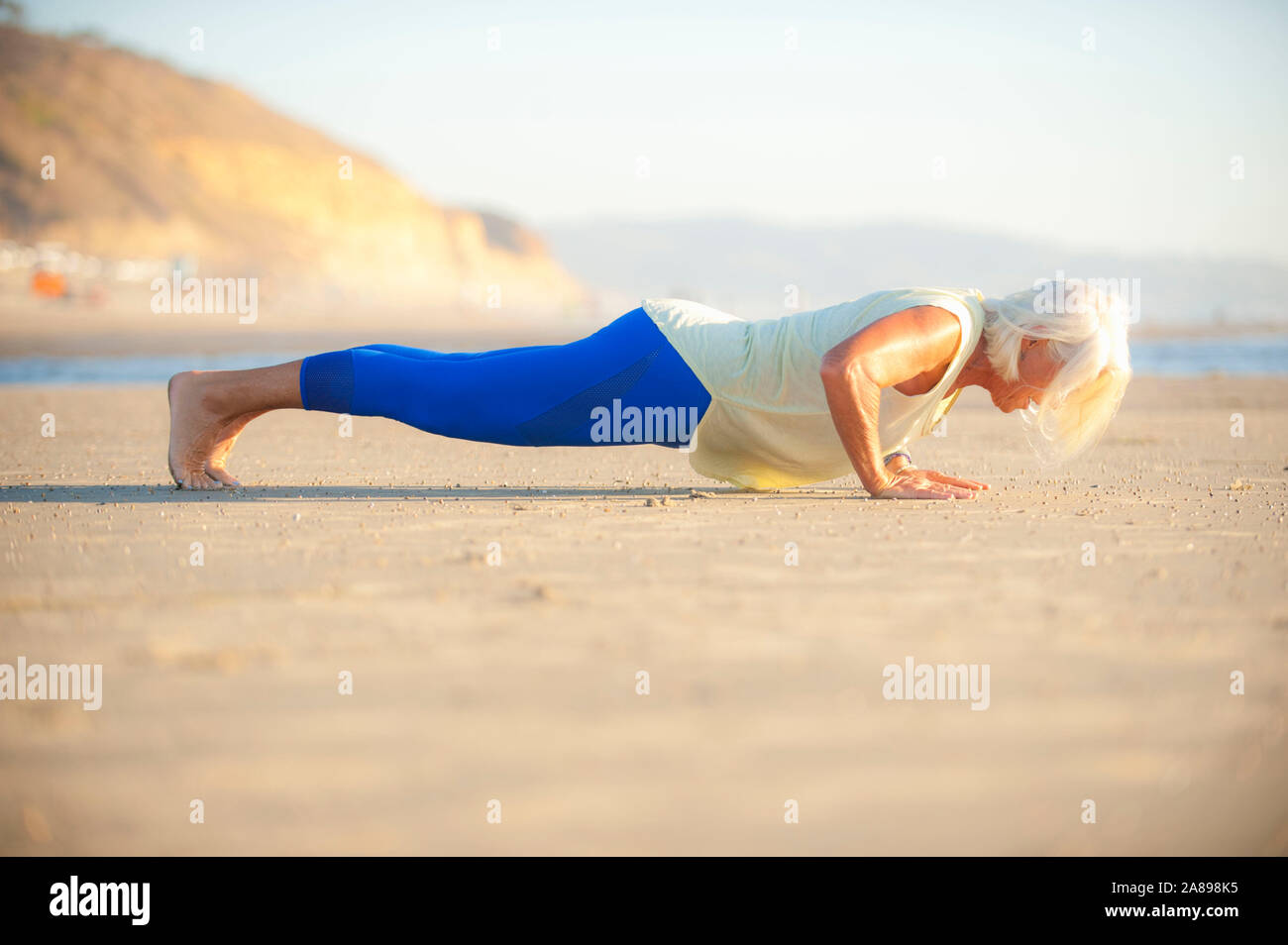 Mature woman doing push-ups on beach Stock Photo