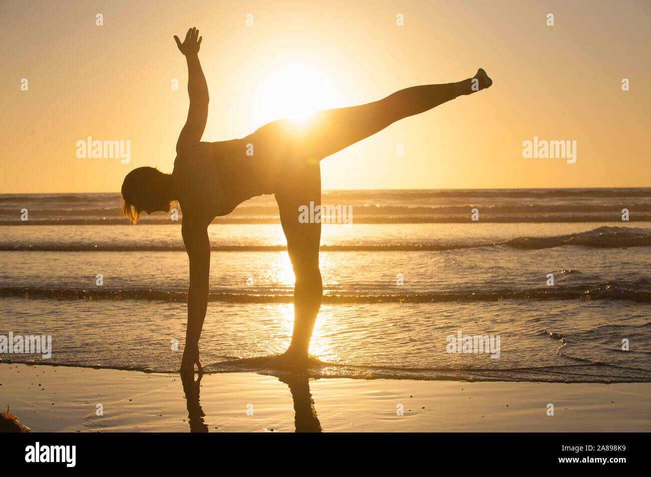 Silhouette of woman doing yoga on beach at sunset Stock Photo - Alamy