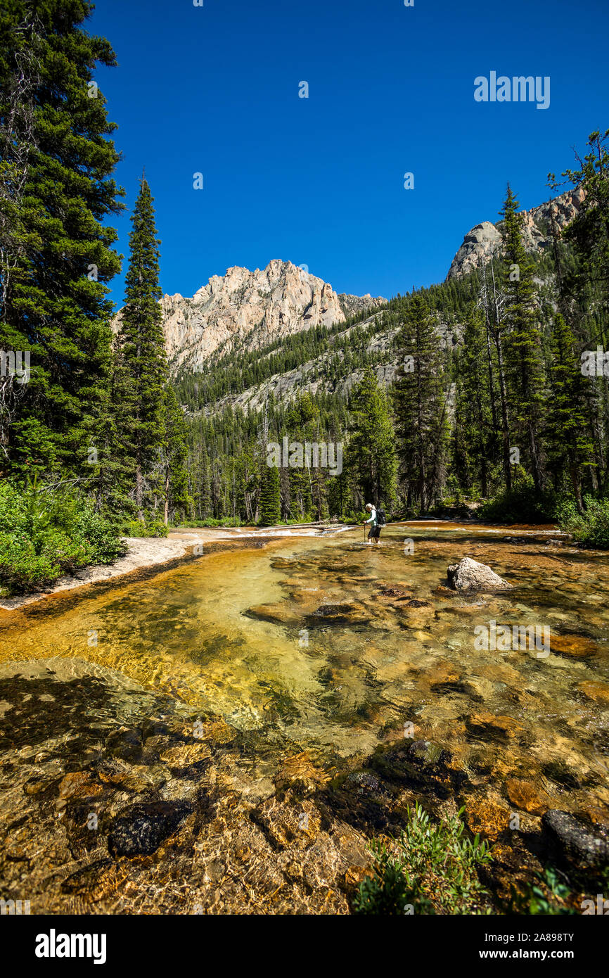 Woman wading through river by Sawtooth Mountains in Stanley, Idaho, USA