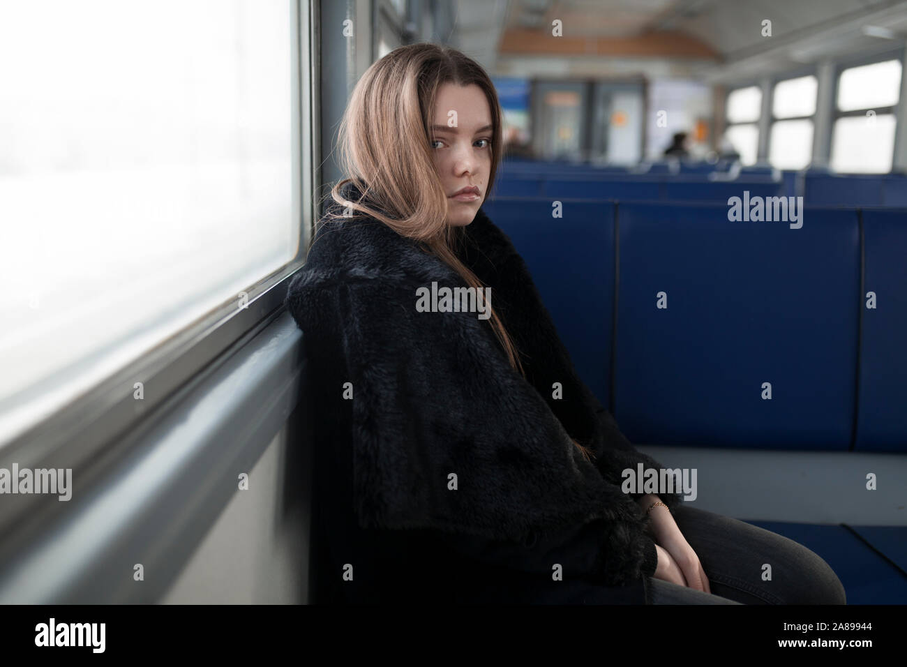 Young woman wearing black fur coat on train Stock Photo