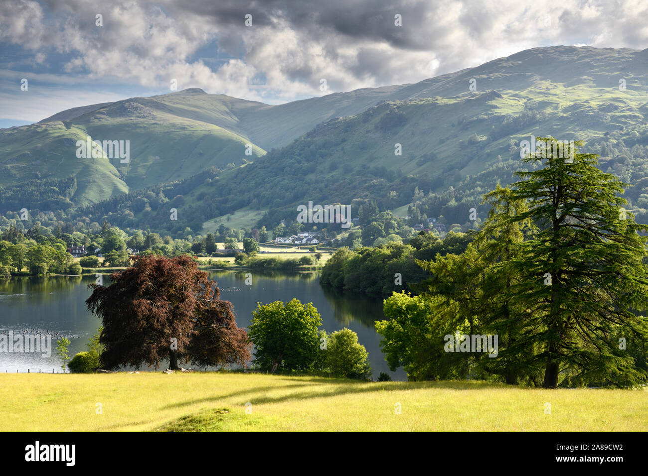 Grasmere Lake on the River Rothay in early morning sunlight with Nab Scar and Great Rigg peaks in the Lake District National Park England Stock Photo