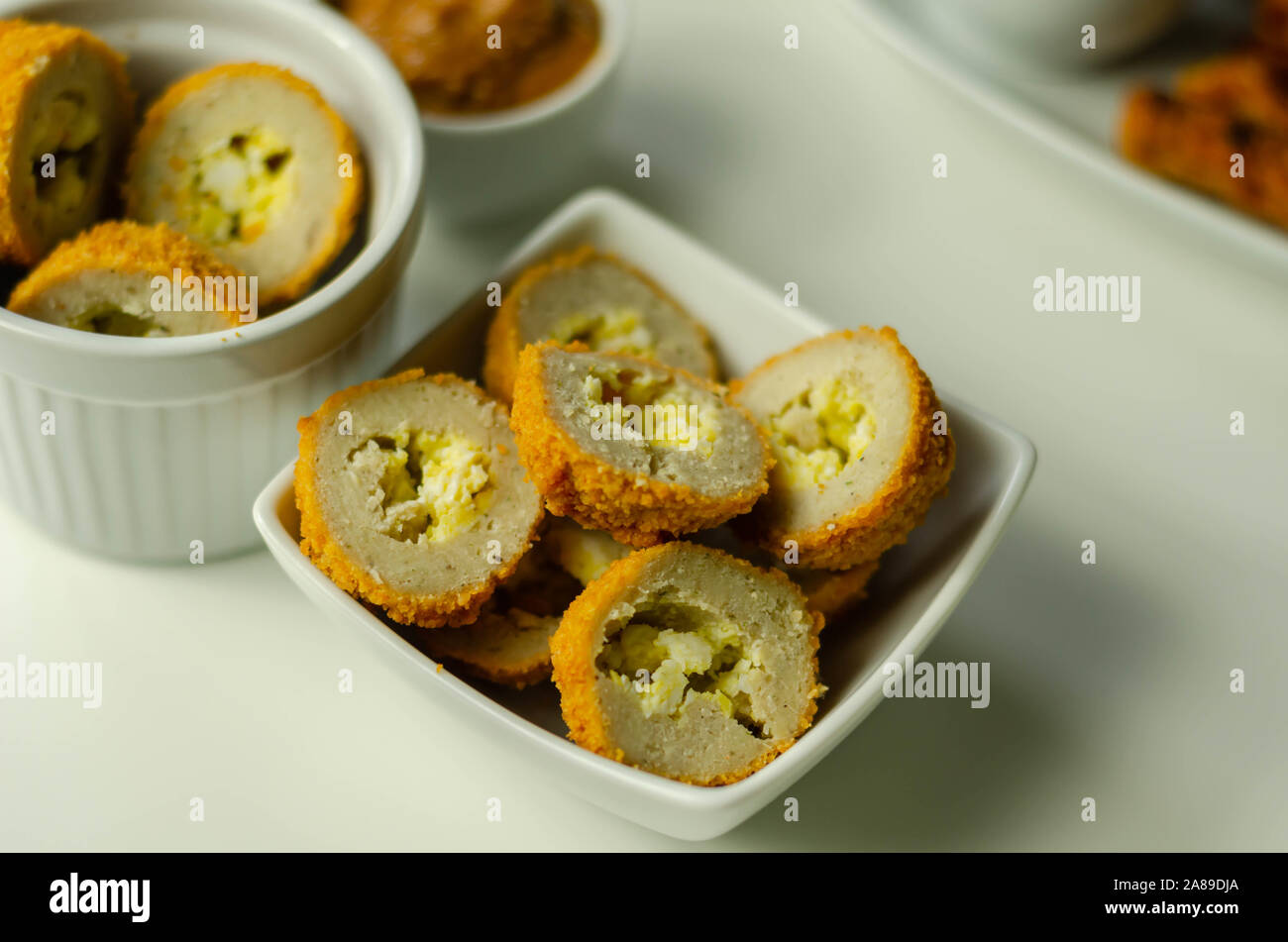 Savory mini scotch eggs in white ceramic bowl, traditional English snack, appetizer Stock Photo
