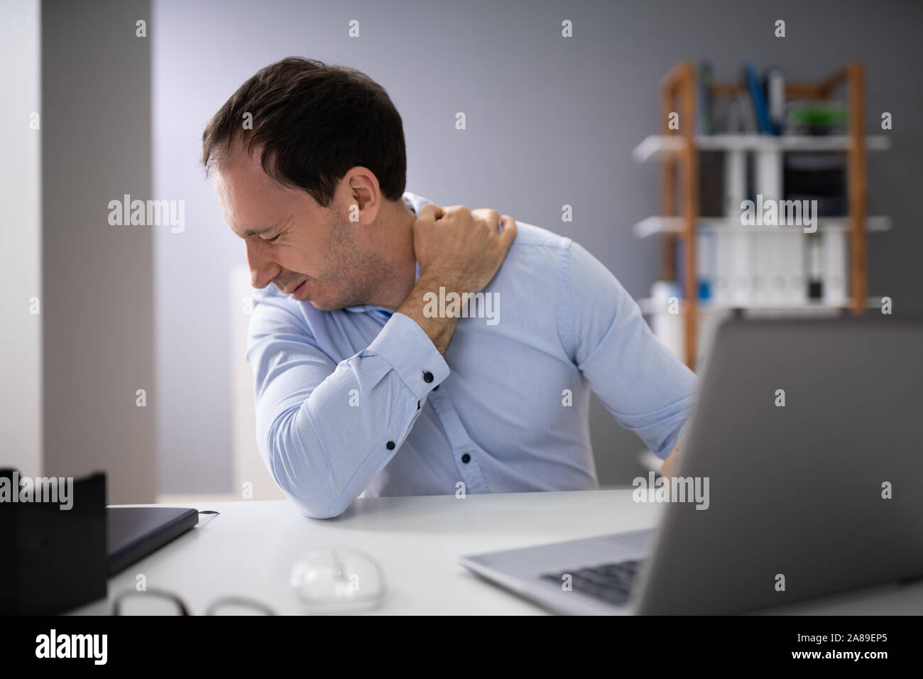 Young Man Suffering From Neck Pain While Working On Laptop Stock Photo Alamy
