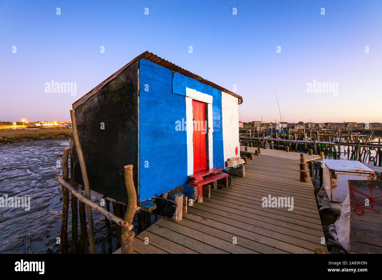 A fisherman hut on a wooden pillars pier, the palafite fishing harbour of Carrasqueira at dusk. Alentejo, Portugal Stock Photo