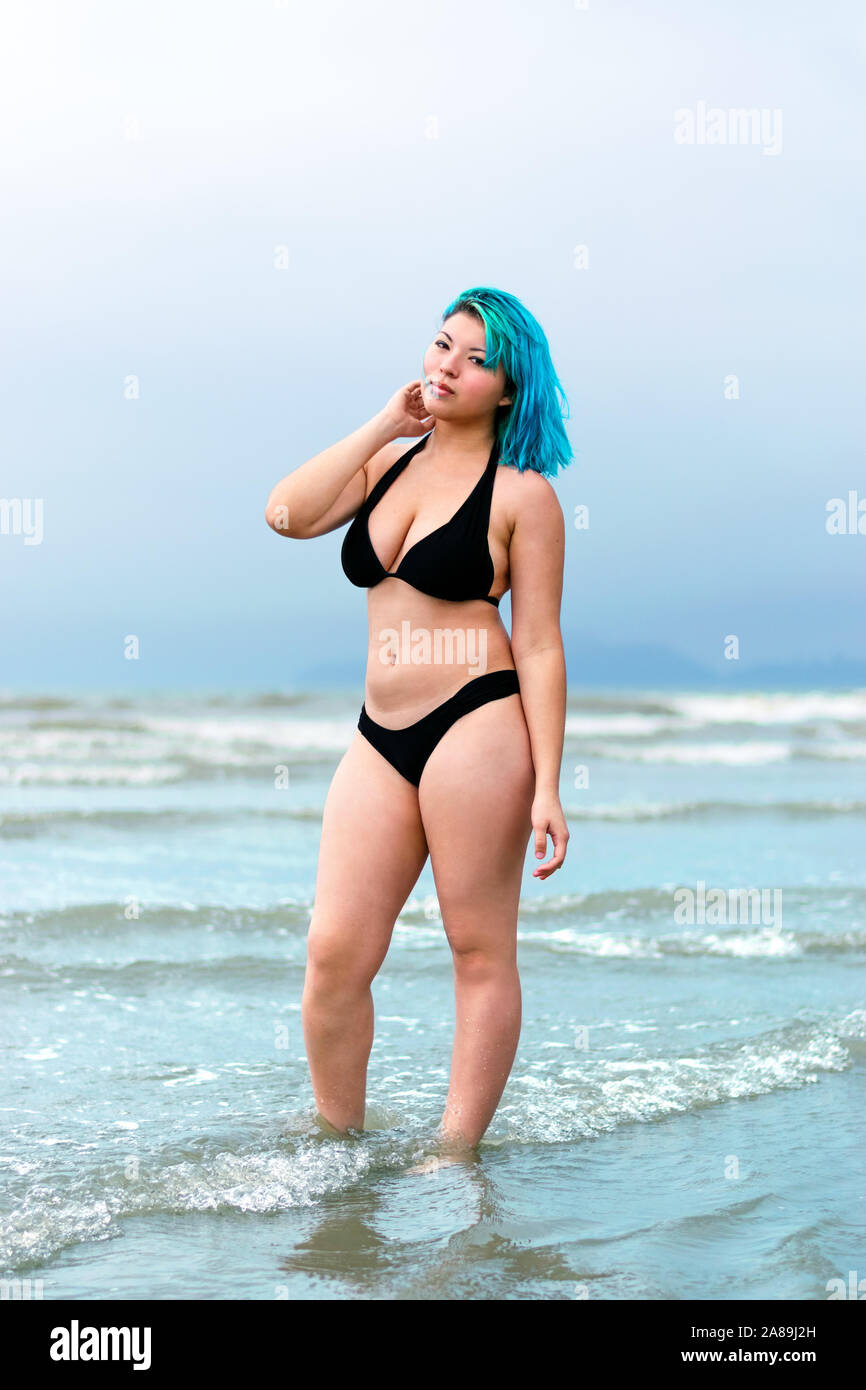 Blue hair girl, beach black bikini model full body shot, with ocean water background Stock Photo