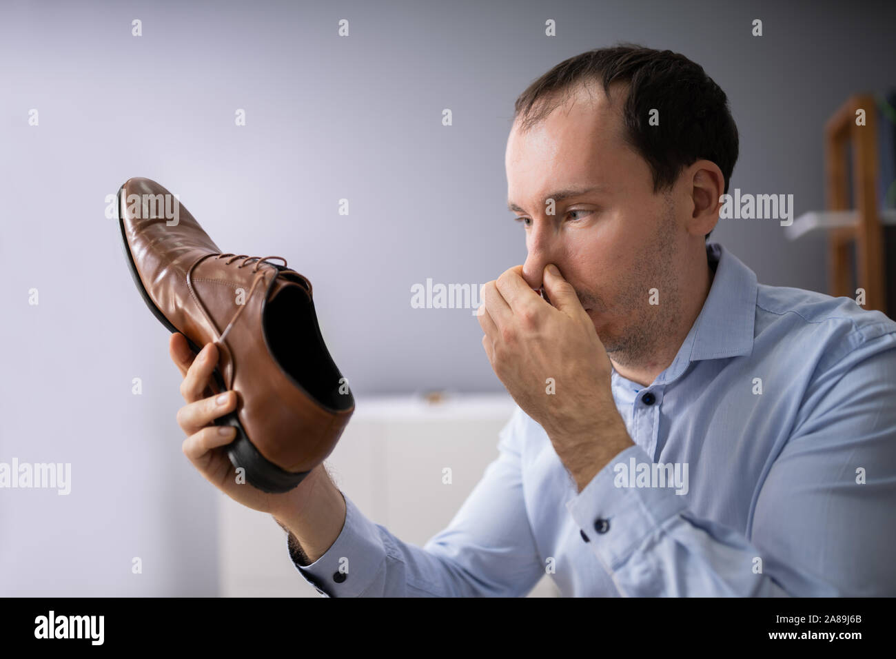 Close-up Of A Young Man Holding Stinky Shoe Stock Photo