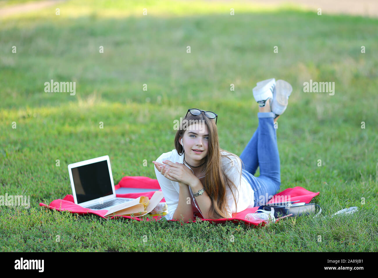 young girl lying on the grass in the park and works at a laptop Stock ...