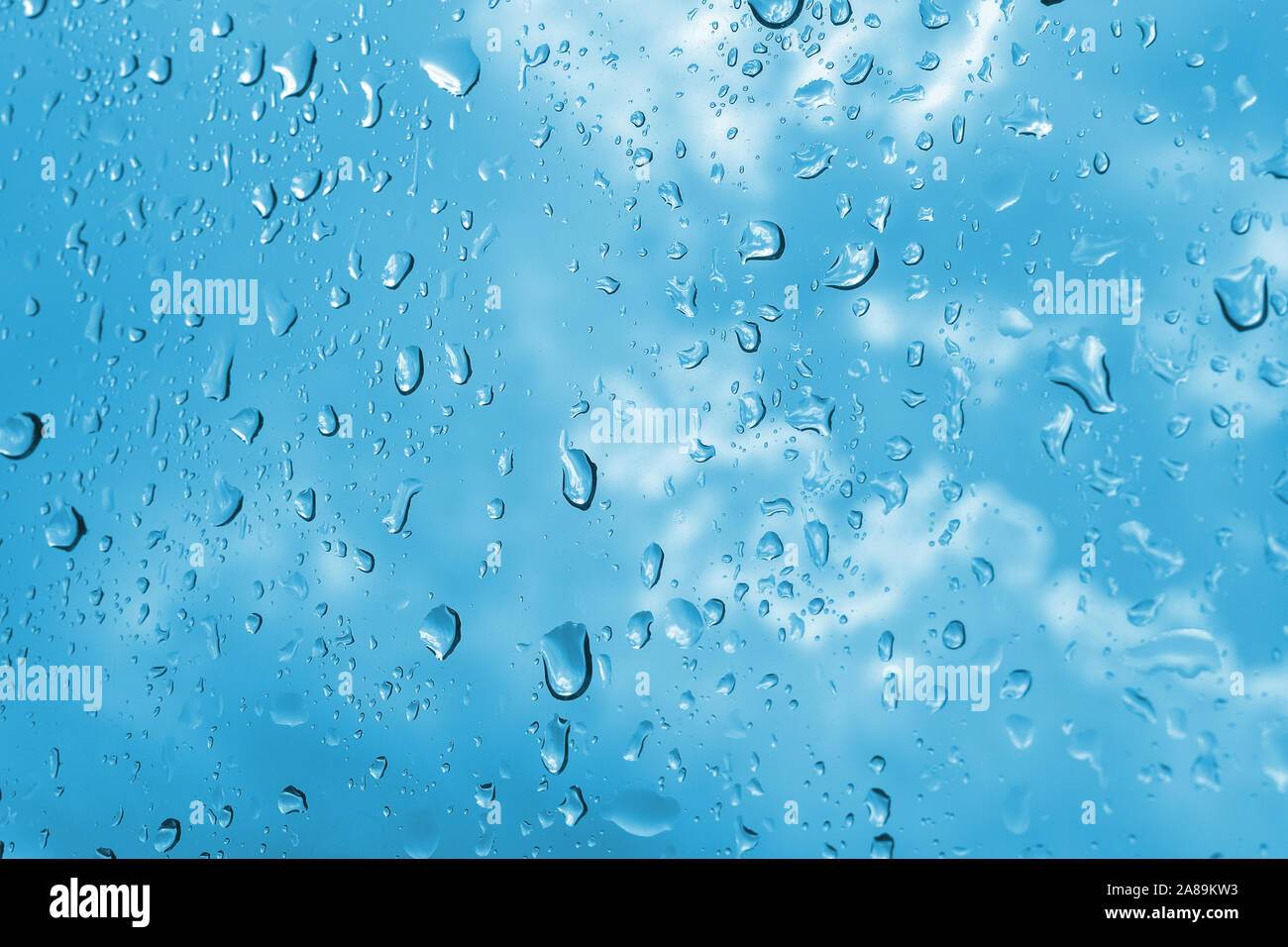 Closeup raindrops in the window glass. Cloudy blue sky in the background. Macro Stock Photo