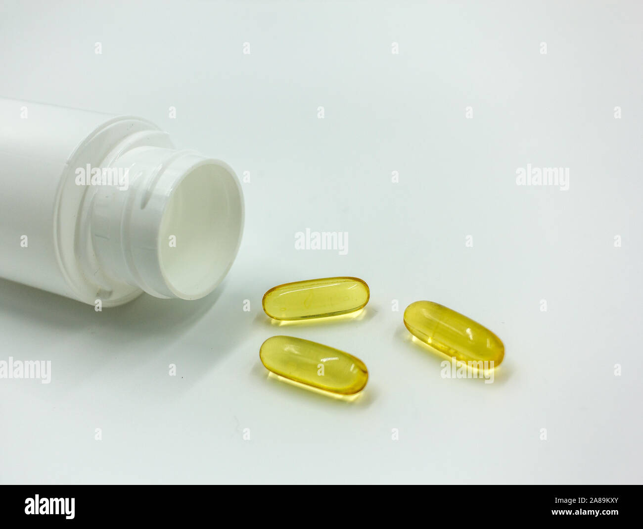 Omega Capsules on White Table Next to Empty Pill Bottle - White Background, Room for Text Stock Photo